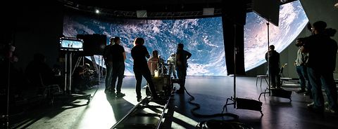 A virtual production setup & behind the scenes of an astronaut-scene in front & a space background.