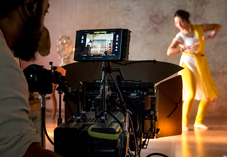 Man filming a dancing woman with a camera that has an ARRI matte box mounted on it