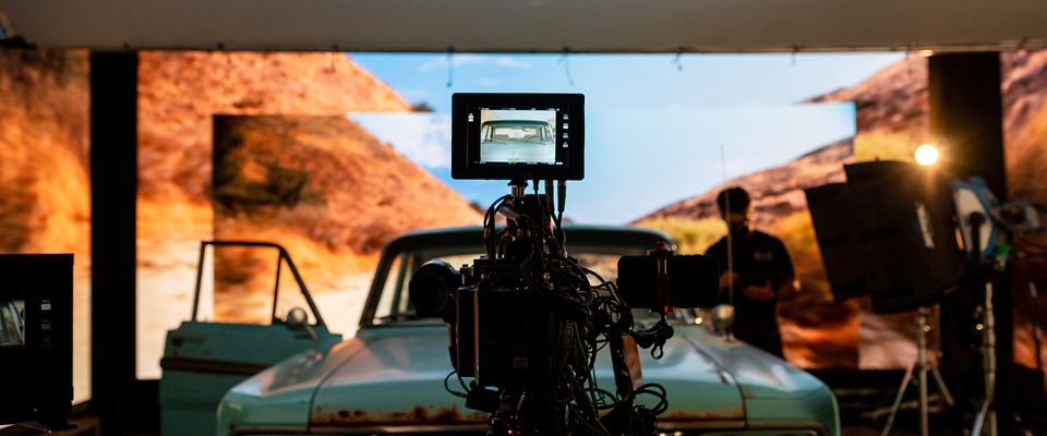 A look into the camera's viewpoirt while fimling a car scene in front of a desert background in a virtual production studio.