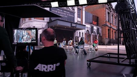 A bts shot of a movie set filming a scene in front of a virtually created cinema while camera position tracking is used.