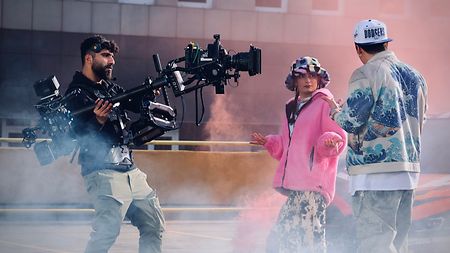 TRINITY operator Omer Belli filming two actors on a rooftop with smoke around them