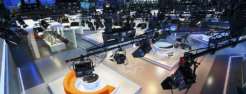 Glance from top of a studio's lighting-installation down to the stage showing the studio and numerous broadcasting equipment.