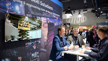 Image of ARRI Solutions team members at an event-booth, presenting their fixed virtual production stage-solutions.
