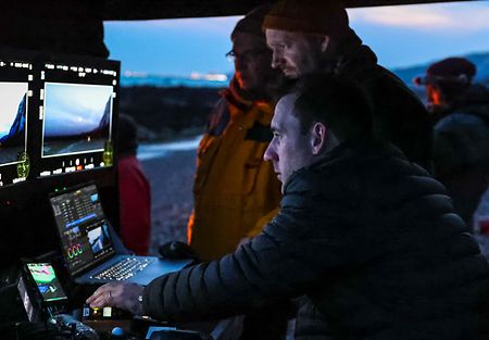 People looking at two screens of the DTI cart on a low-lit movie set