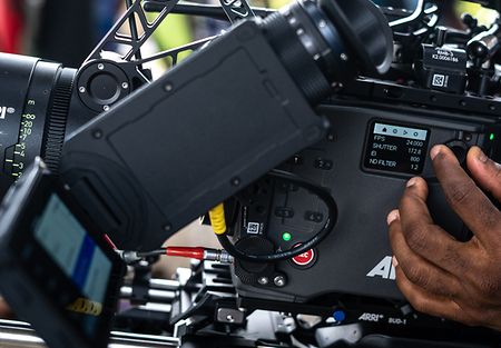 An image from a movie set showing MVF-2 in the foreground and a hand operating the side screen of ALEXA 35 camera.